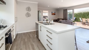 Een moderne keuken met witte kasten, een centraal eiland en een eethoek met uitzicht op de omgeving.