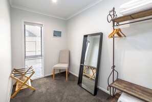 A room with a large mirror, a chair, a wooden drying rack, and a coat rack. - Citron 9, Greytown, Wairarapa (Greytown)