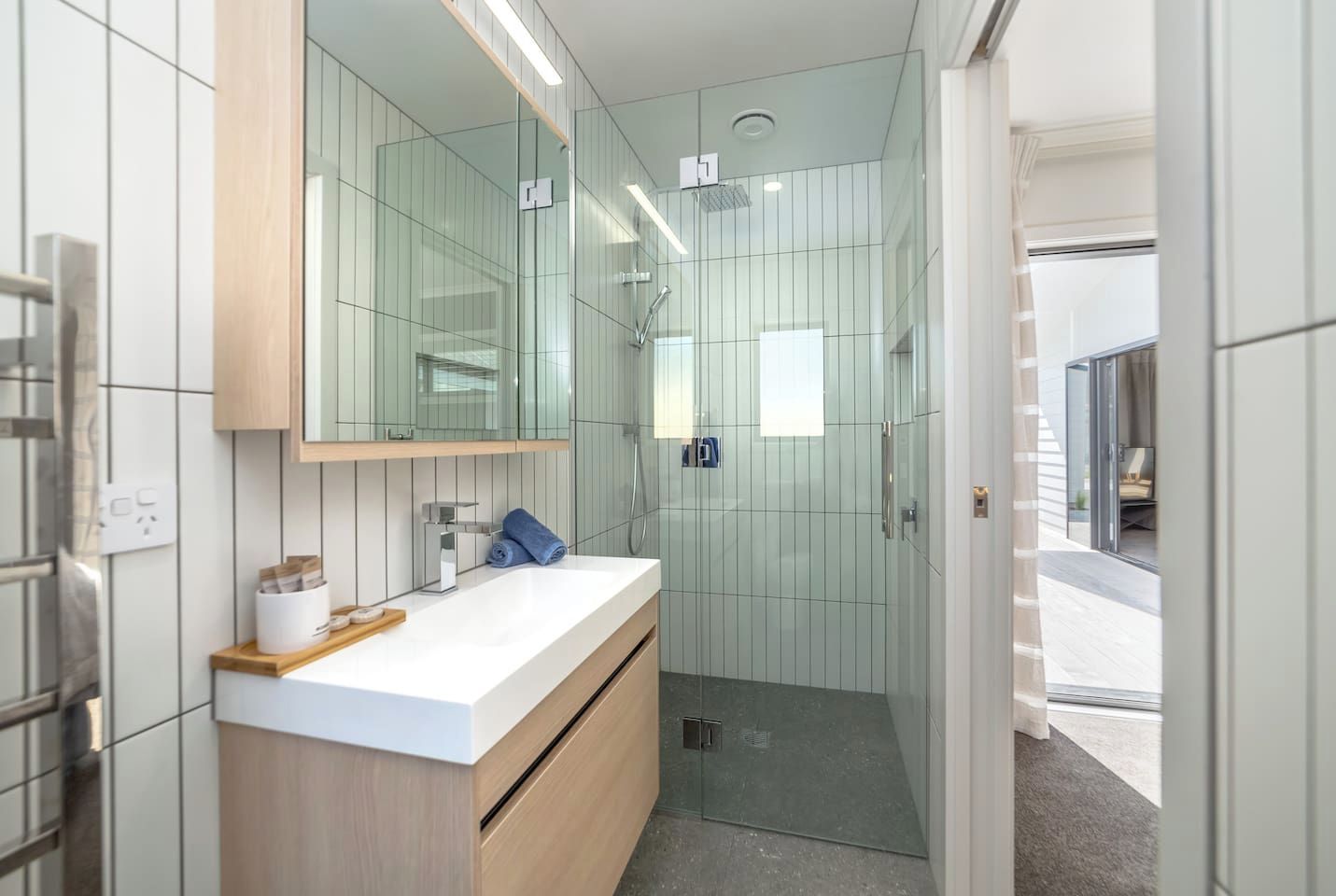 A modern bathroom with a glass shower enclosure, a white vanity with a mirror, and a wooden countertop.