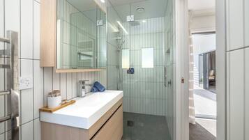 A modern bathroom with a glass shower enclosure, a white vanity with a mirror, and a wooden countertop.