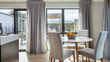 A modern dining area with a round table, grey upholstered chairs, and a bowl of fruit.