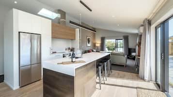 A modern kitchen with a central island, stainless steel appliances, and a dining area with a sofa and TV.