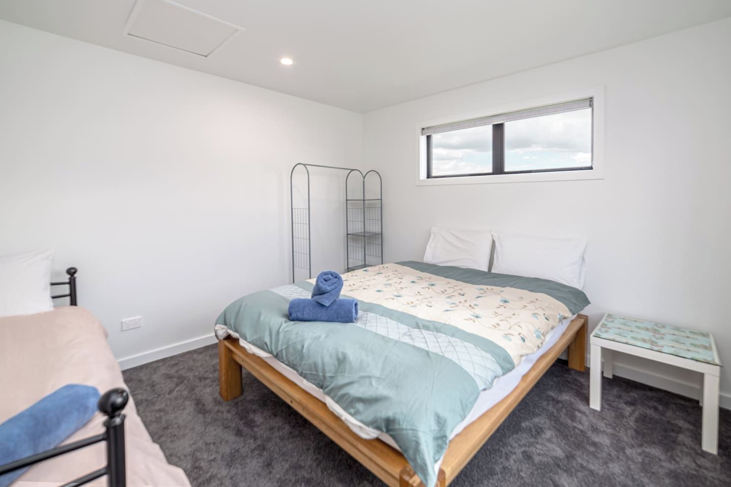 A bedroom with a bed, a bedside table, a chair, a window, and a wardrobe.
