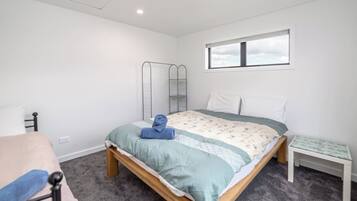 A bedroom with a bed, a bedside table, a chair, a window, and a wardrobe.