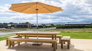 A wooden deck with a picnic table and an umbrella.