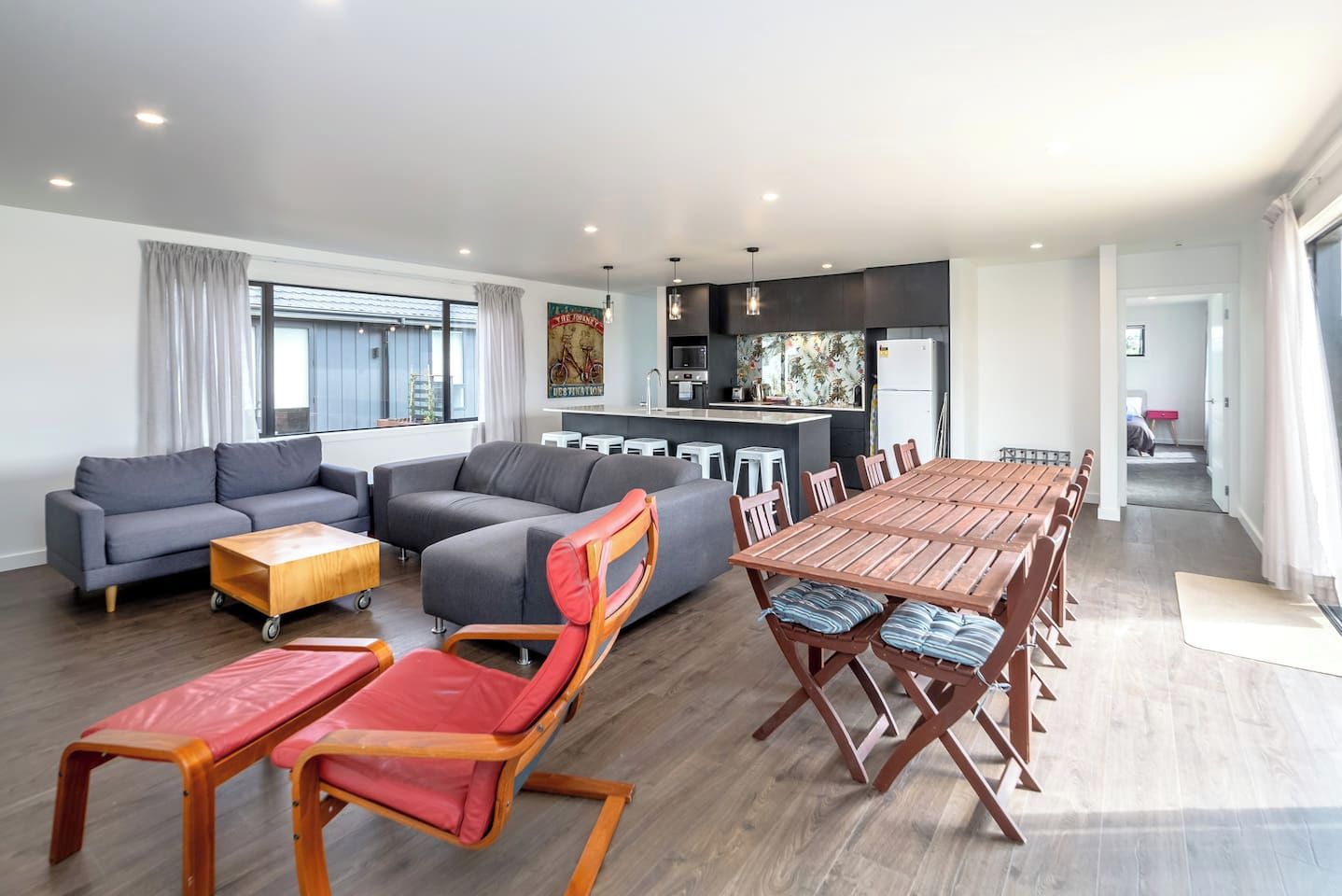 A modern living room with a sofa, a dining table, and a kitchen area.