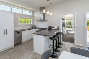 A modern kitchen with a central island, bar stools, and a dishwasher. - Easy Days Martinborough (Martinborough)