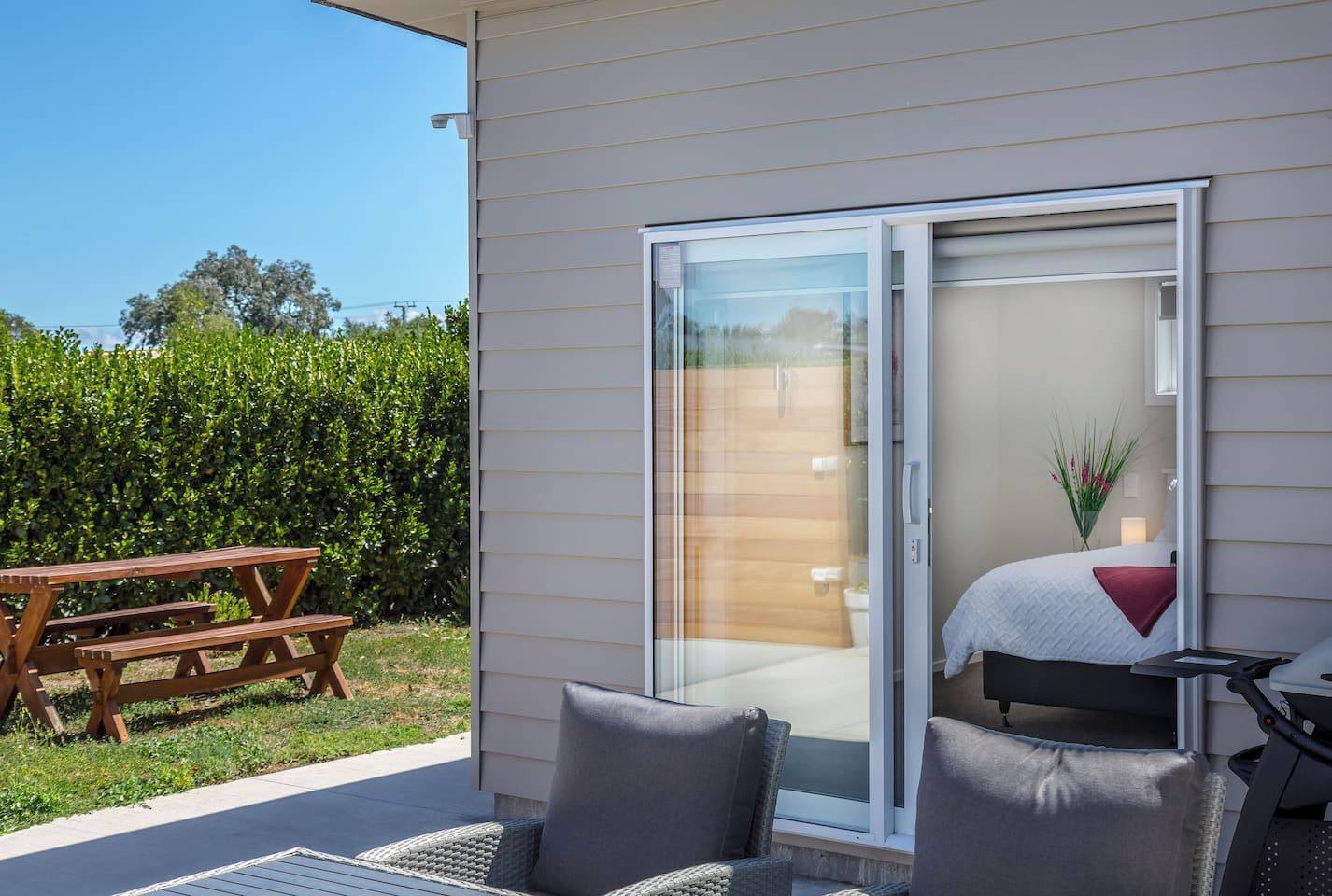A patio with a sliding glass door leading to a bedroom, a wooden table, and outdoor seating.