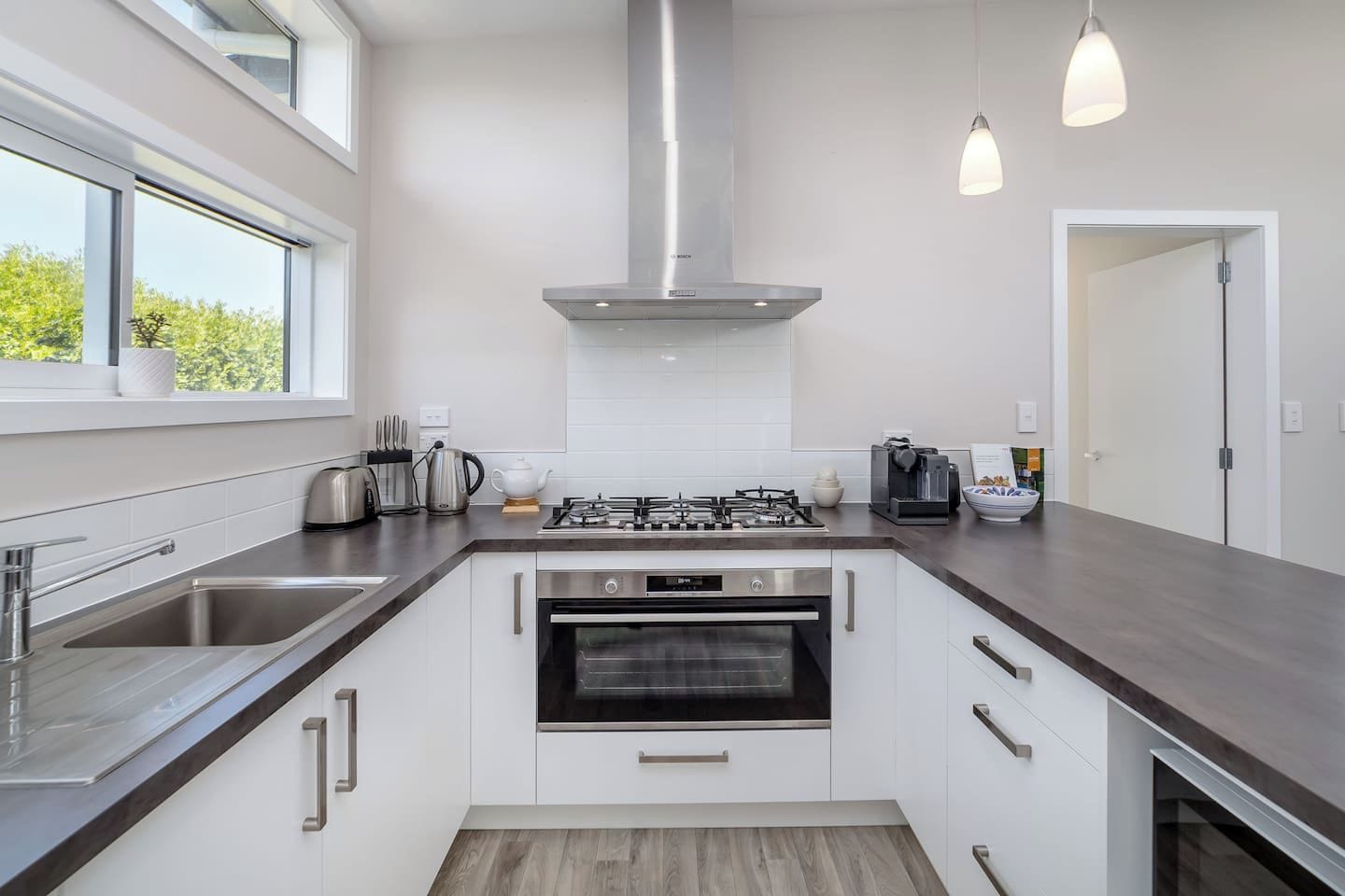 Una cocina moderna con electrodomésticos de acero inoxidable, estufa a gas, horno y un amplio ventanal que proporciona luz natural.