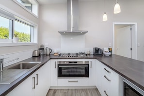 A modern kitchen with stainless steel appliances, a gas stove, an oven, and a large window providing natural light.