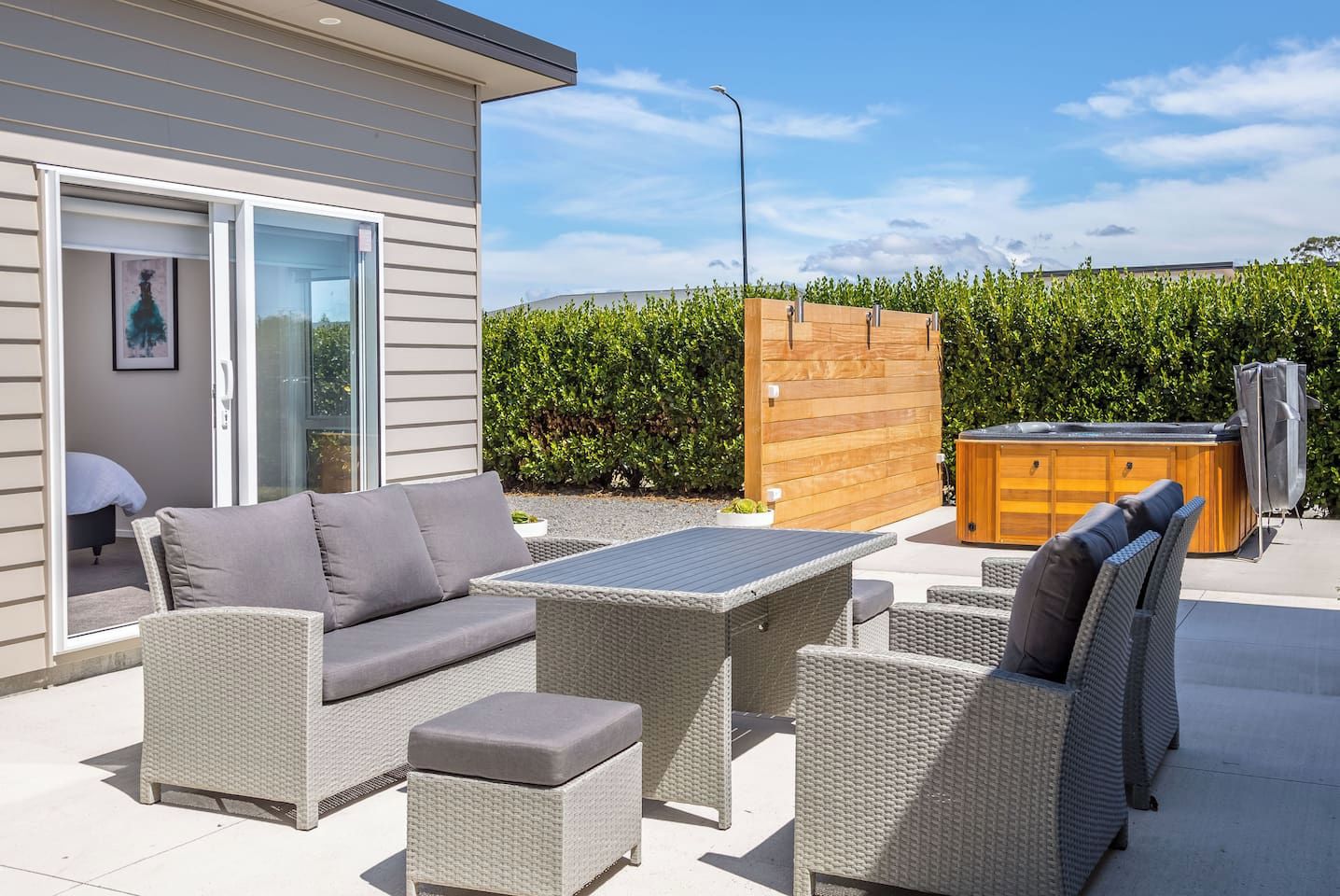 Un patio al aire libre con mobiliario de mimbre, un jacuzzi y una terraza de madera.