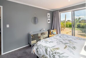 Un dormitorio con cama, cómoda, ventana con cortinas y vistas al exterior.