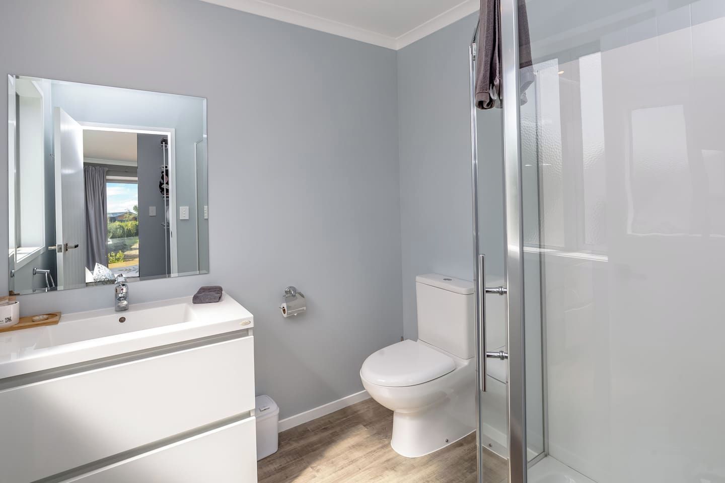 A bathroom with a white sink, mirror, toilet, and glass shower enclosure.
