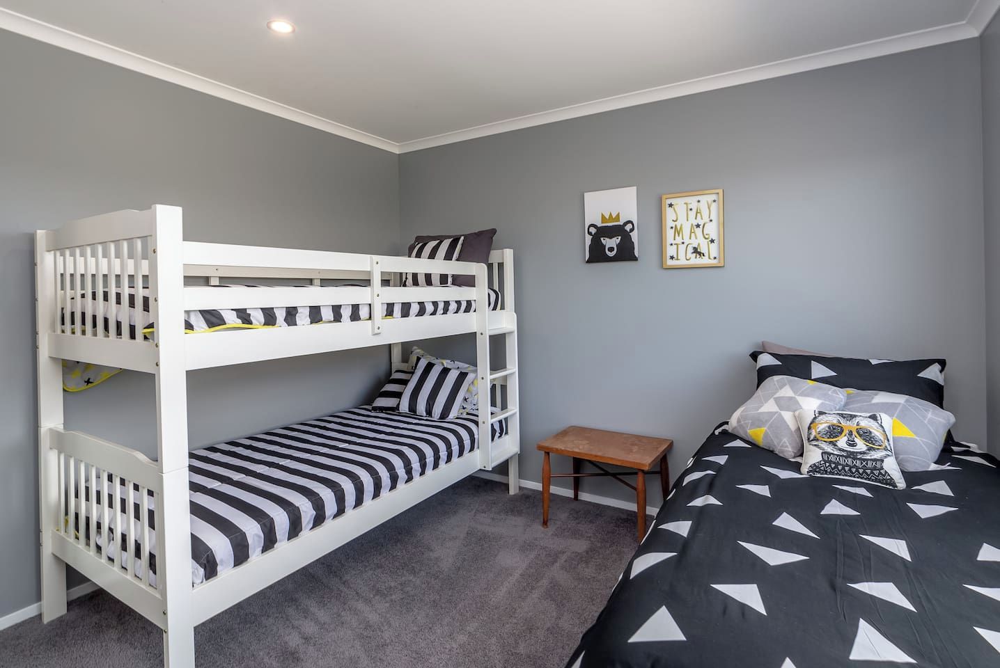 A room with bunk beds, a small wooden table, and two wall decorations.
