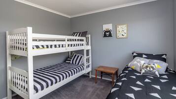 A room with bunk beds, a small wooden table, and two wall decorations.