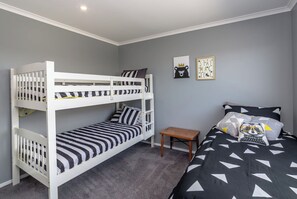 A room with bunk beds, a small wooden table, and two wall decorations. - Fern Haven, Martinborough (Martinborough)