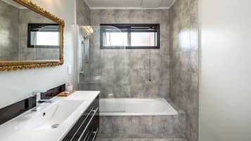 A modern bathroom with a double vanity, a freestanding bathtub, and a large mirror with a decorative frame.