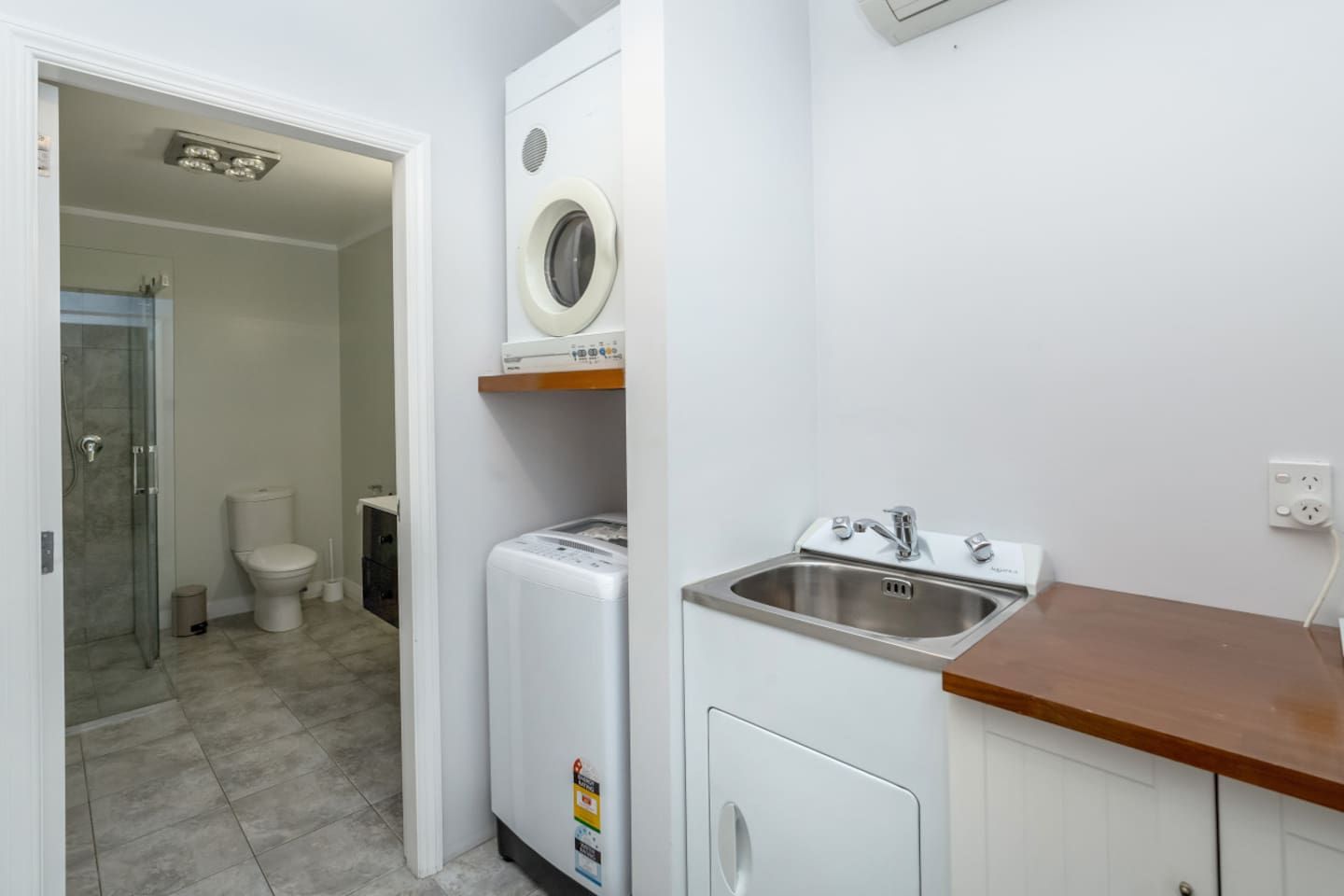 A compact bathroom with a toilet, a washing machine, and a sink.