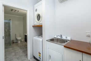 A compact bathroom with a toilet, a washing machine, and a sink. - Bronte House, Martinborough (Martinborough)