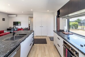 A modern kitchen with a built-in dishwasher, a large island with a sink, and a view of the outdoors through a large window.