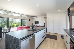 A modern kitchen with a marble countertop, stainless steel appliances, and a large window providing a view of the outdoors. - Burgundy Place, Martinborough (Martinborough)