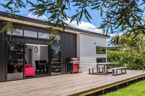 A modern house with a deck, a barbecue, and outdoor seating.