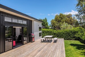 A modern outdoor deck with a barbecue grill, seating area, and a view of the surrounding greenery. - Burgundy Place, Martinborough (Martinborough)