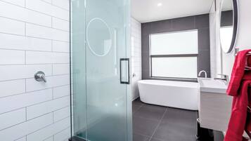 A modern bathroom with a glass shower enclosure, a bathtub, and a large mirror.