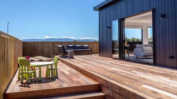 Eine moderne Terrasse im Freien mit Holzboden, Tisch mit Stühlen und einer Sitzecke.