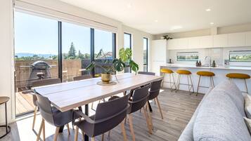 A modern kitchen with a large island, bar stools, and a dining area with a table and chairs.