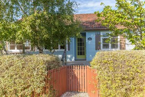 A two-story house with a green door and a red picket fence. - Strasbourge Cottage, Martinborough (Martinborough)