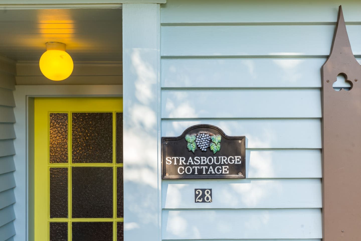 A house with a yellow door and a sign reading 'Strasbourg Cottage' with the number 28.