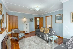 A living room with a sofa, a coffee table, a side table, a cabinet, and a rug. - Strasbourge Cottage, Martinborough (Martinborough)