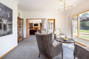 A room with a fireplace, a television, wicker furniture, and a large window with curtains.