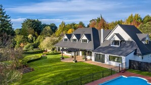 Une maison moderne dotée d’un grand jardin, d’une piscine et d’un patio couvert.
