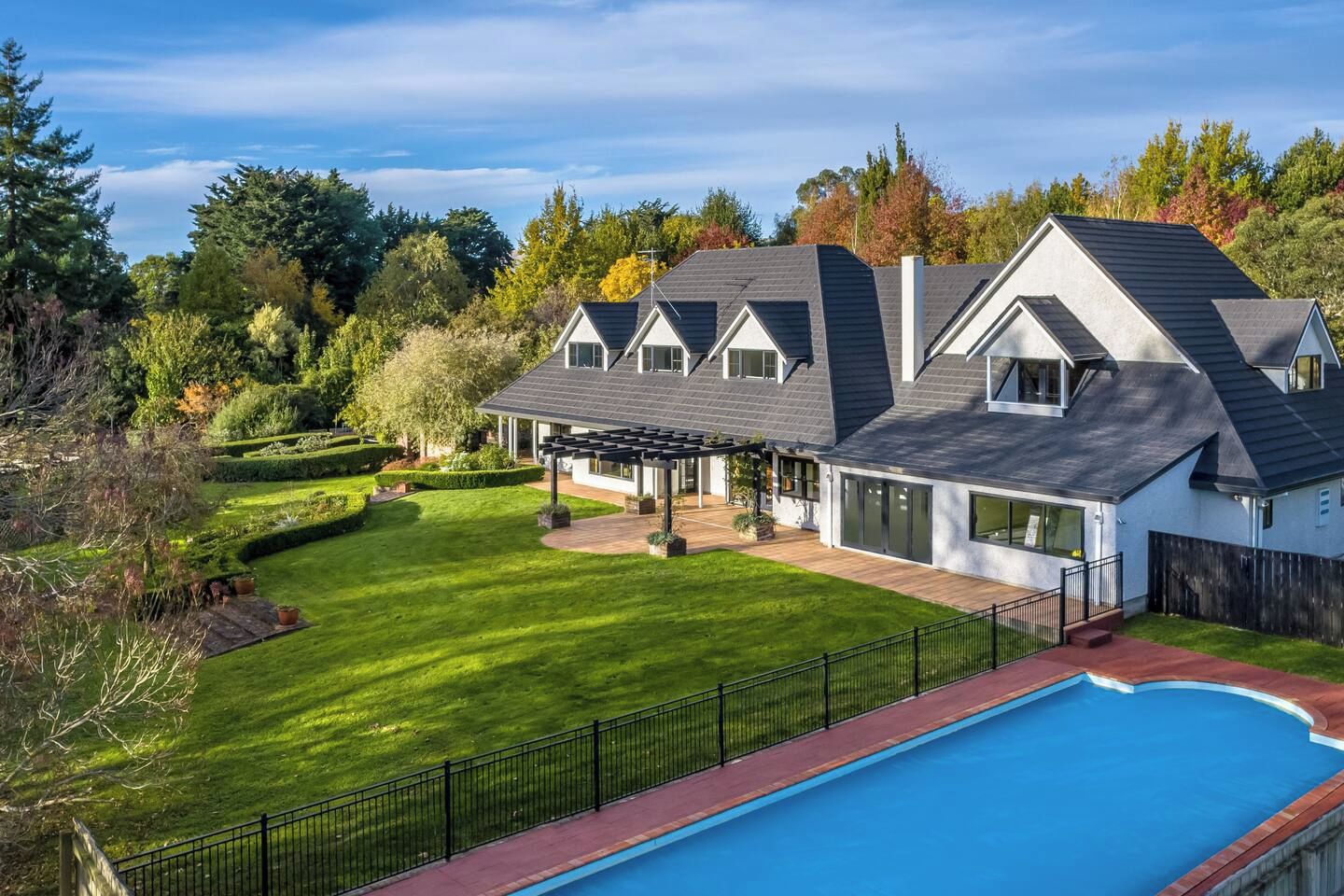 A modern two-story house with a large backyard, a swimming pool, and a well-maintained garden.