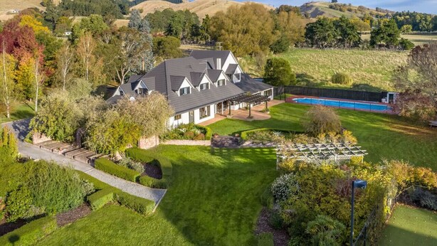 Une grande maison avec une pelouse bien entretenue, une piscine et une vue sur des collines ondoyantes.