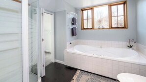 A bathroom with a bathtub, a window, and a door leading to another room. - Longbush Estate, Gladstone (Longbush)