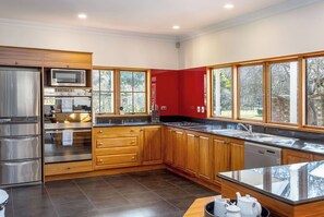 A modern kitchen with stainless steel appliances, wooden cabinets, and large windows.