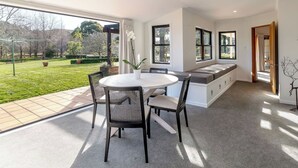 A modern kitchen with a dining area, large windows, and a view of the garden. - Longbush Estate, Gladstone (Longbush)