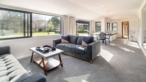 Un salon moderne avec un canapé gris, une table basse et un coin repas comprenant une chaise et une table.