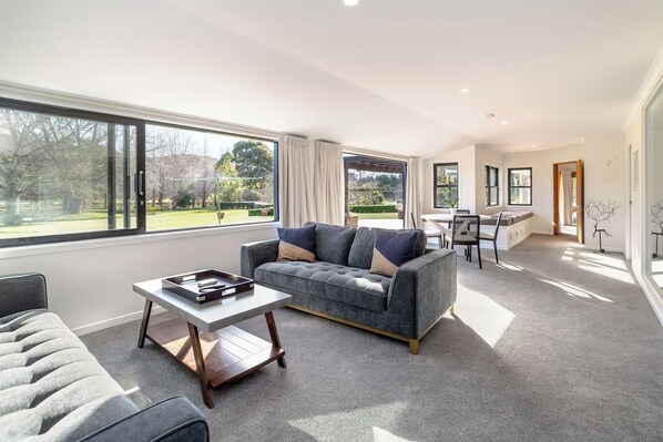 A modern living room with a grey sofa, a coffee table, and a dining area with a table and chairs.