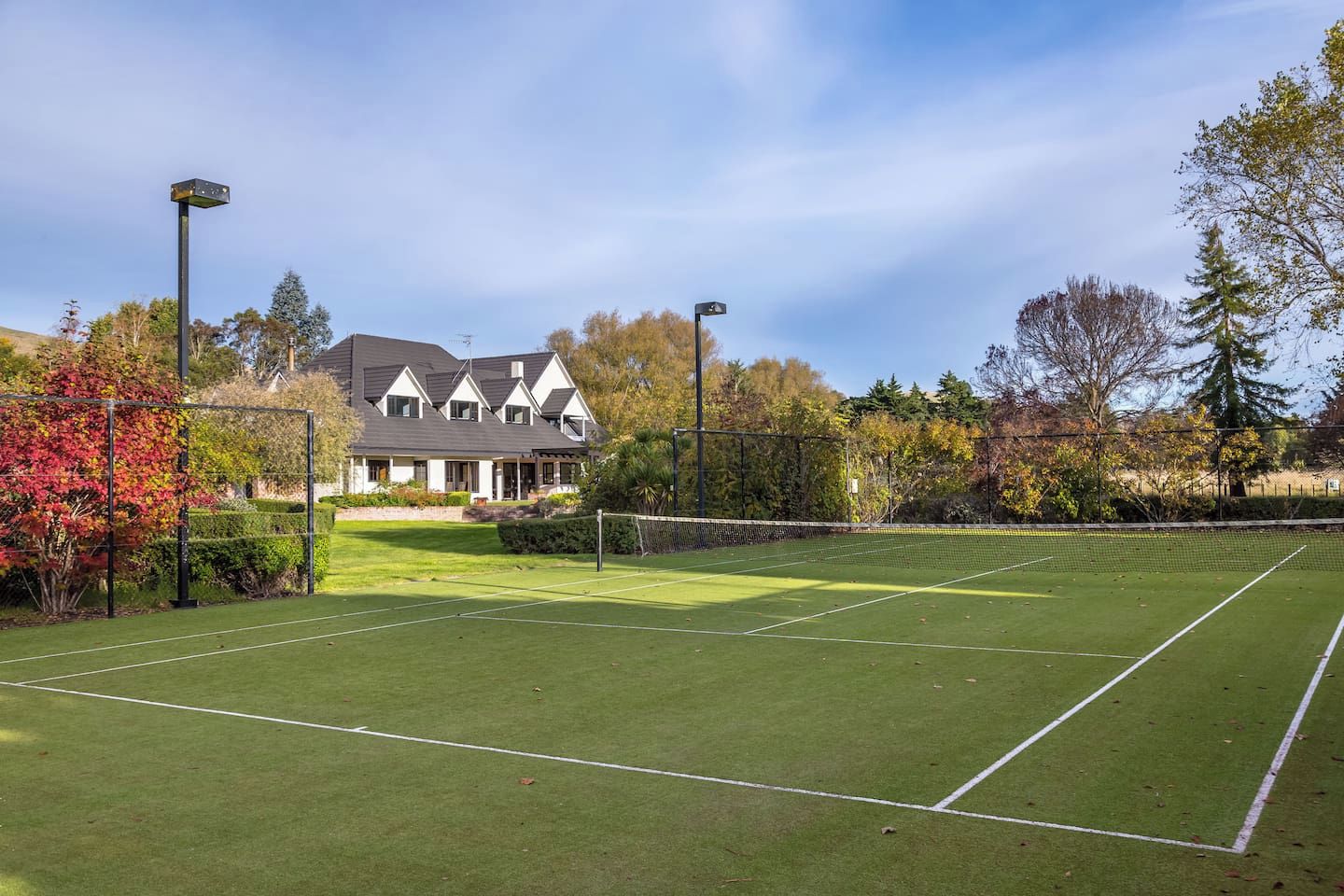 A tennis court with a house in the background.