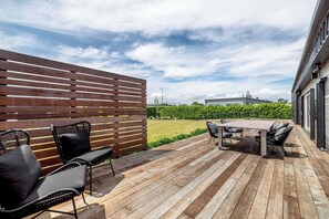An outdoor patio with a wooden deck, a table with chairs, and a wooden fence.