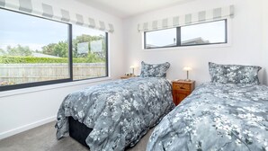 Une chambre avec deux lits, une grande fenêtre et un miroir.