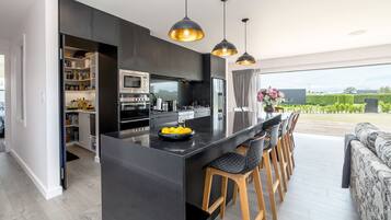 A modern kitchen with a central island, bar stools, and a dining area with a view.
