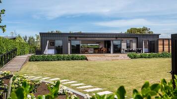 A modern two-story house with a covered patio, a wooden deck, and a well-maintained lawn.