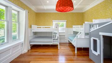 A room with bunk beds, a window, and a red hanging light fixture.