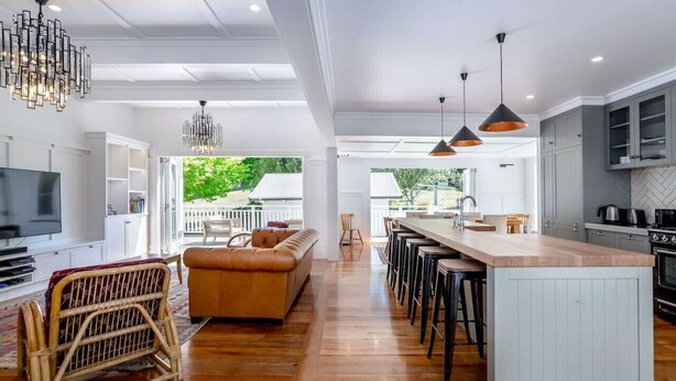 A modern kitchen with a central island, bar stools, and a dining area. - The Forest House, Martinborough (Pirinoa)
