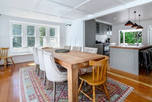 A modern kitchen with a wooden island, white cabinetry, and a large window providing natural light. - The Forest House, Pirinoa (Pirinoa)